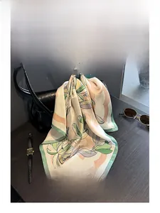 Detail of silk scarf with magnolia print paired with black leather bag on dark wood