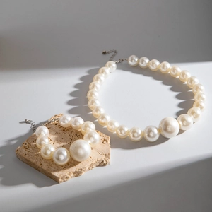 Elegant white faux pearl necklace and bracelet set featuring a large center pearl