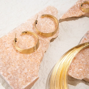 Gold multi-layered round necklace and earring set displayed on pink crystal stone