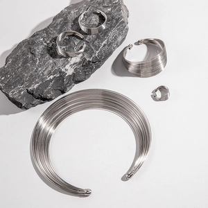 Macro shot of silver multi-layer metal jewelry set on grey stone against white backdrop