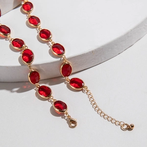 Dettaglio collana dorata con pietre preziose rosse ovali e chiusura a moschettone