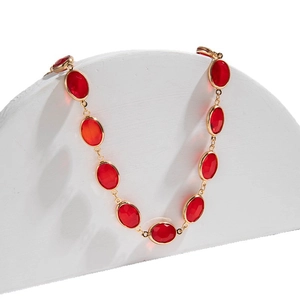 Collana di perle con ciondoli di pietre rosse ovali su un elegante supporto bianco