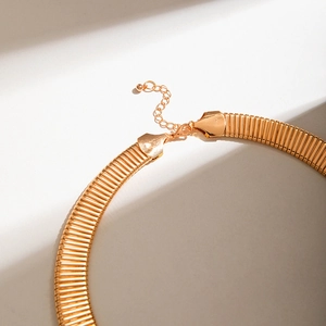 Detail of gold choker necklace featuring textured metal bands and adjustable lobster clasp