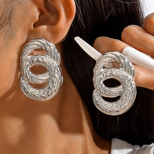 Détail de boucles d'oreilles torsadées argentées au fini martelé sur un mannequin