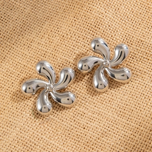 Gros plan de boucles d'oreilles fleurs argentées à cinq pétales sur fond beige