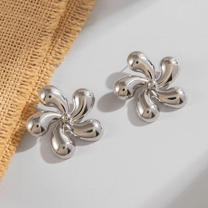 Gros plan de boucles d'oreilles fleur argentées à cinq pétales avec surface polie brillante