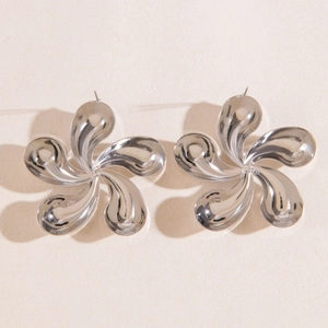 Détail macro de boucles d'oreilles fleurs argentées à cinq pétales torsadées, fini poli