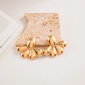 Détail de boucles d'oreilles en métal doré poli sur support en pierre naturelle