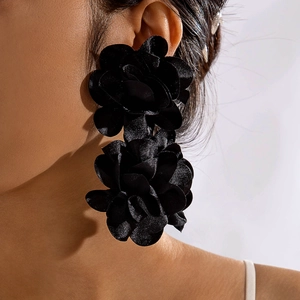 Gros plan de boucles d'oreilles rose en tissu noir avec pétales superposés et fini satiné