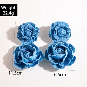 Détail de boucles d'oreilles fleurs 3D en denim bleu rétro avec bords effilochés