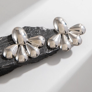 Détail de boucles d'oreilles argentées géométriques sur une pierre noire texturée