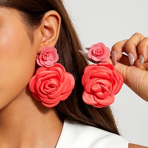 Détail de boucles d'oreilles roses 3D en tissu rouge portées pour un look mode