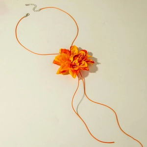 Close-up of a large orange gradient camellia fabric choker with a matching woven cord