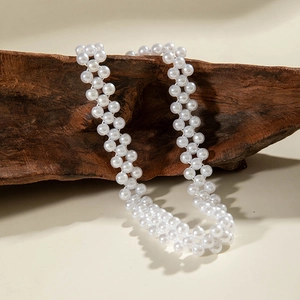 Detailed view of double-strand white faux pearl necklace on natural wood background
