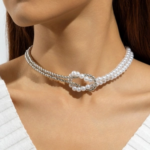 Close-up of double-layered necklace with white pearls and silver beads in a knot design