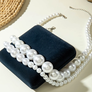 Macro view of multi-layer faux pearl necklace with silver lobster clasp on a velvet jewelry box