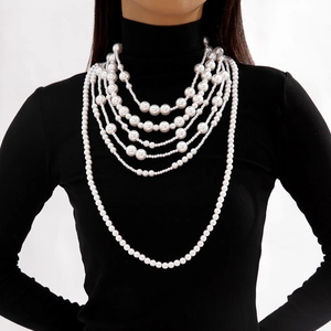 Close-up of elegant multi-layer faux pearl necklace draped over a black turtleneck