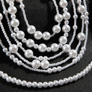 Close-up of layered faux pearl necklace with glossy cream-white beads on black background