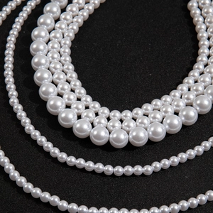 Close-up of layered multi-strand pearl necklace with lustrous white cream beads on black background