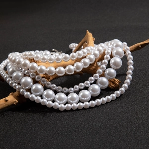 Artistic detail of layered white pearl necklace draped on natural wood branch texture