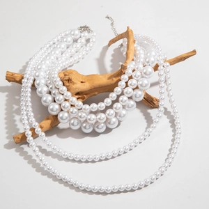Detail of four-layer faux pearl necklace with lobster clasp on a natural wood branch