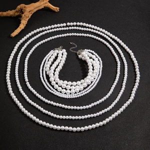 Detail of layered white pearl necklace set with silver clasps on black texture background