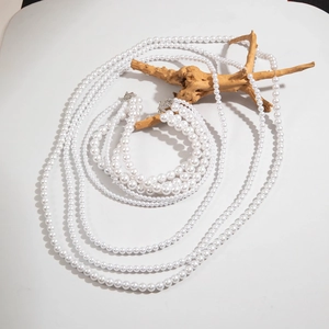 Macro shot of multi-layered faux pearl necklaces draped over natural wood for detail