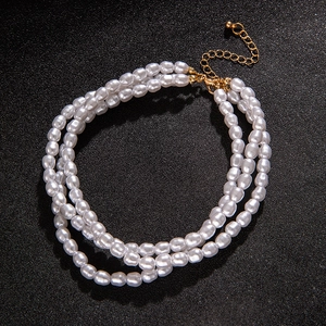 Detail of triple-layer pearl necklace with golden lobster clasp and adjustable chain