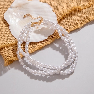 Close-up of a triple-layer pearl necklace with golden lobster clasp and adjustable chain