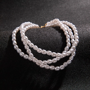 Close-up of triple-layer faux pearl necklace with gold lobster clasp and iridescent finish