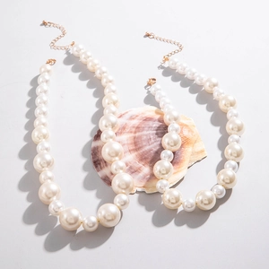 Detail of layered pearl necklace with gold adjustable lobster clasp on shell background
