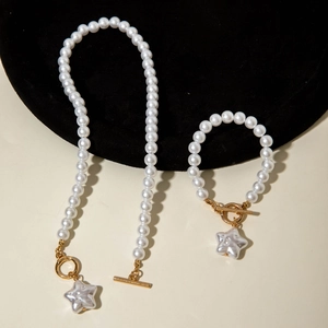 Dettaglio del set di collana e bracciale di perle con chiusura OT dorata e ciondolo a stella