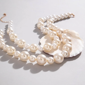 Detail of double-layer cream pearl necklace with gold lobster clasp and extension chain