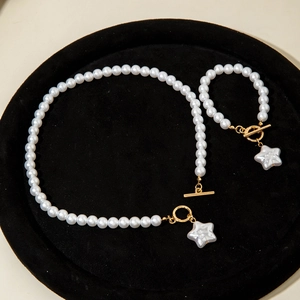 Dettaglio di set collana e bracciale di perle con chiusura a ginocchiera dorata