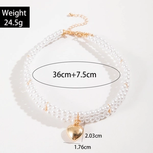 Detailed view of triple-layer pearl necklace with gold heart pendant and lobster clasp