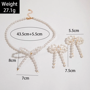 Set di gioielli con fiocco di perle con collana e orecchini pendenti su sfondo neutro