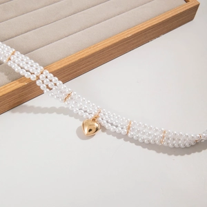 Detailed view of triple-layered pearl necklace with a polished gold heart pendant