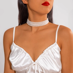 Close-up of elegant four-layer white pearl choker necklace on a female model
