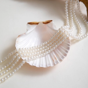 Detailed view of layered faux pearl necklaces with elegant white shell decorative props