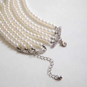 Detail of multi-layer faux pearl necklace showing silver lobster clasp and extender chain