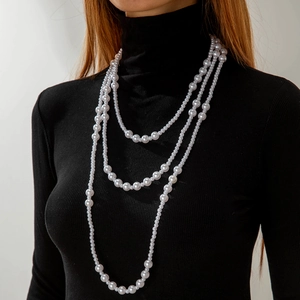 Detail view of a triple-layered pearl necklace on a black turtleneck top