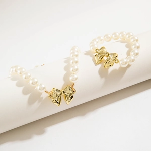 Dettaglio del set collana e bracciale di perle con ciondoli a farfalla dorati