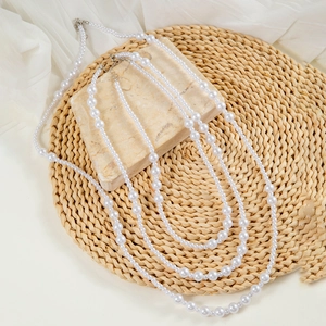 Detail of elegant multi-layer white faux pearl necklace with silver metal clasp