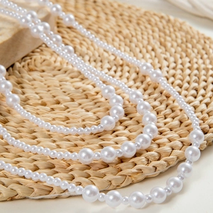 Close-up of layered faux pearl necklace showing elegant luster on a natural background