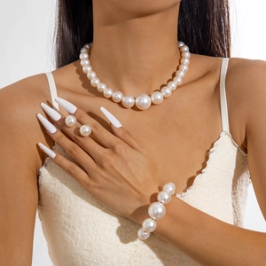 Set collana e bracciale di perle bianche lucide indossato da modella in pizzo bianco