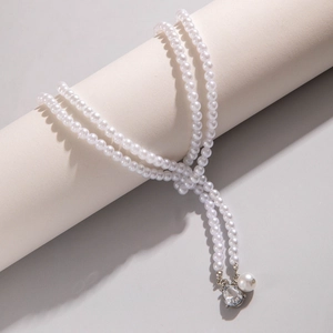 Detail of multilayer pearl necklace with teardrop gemstone and round pearl pendant
