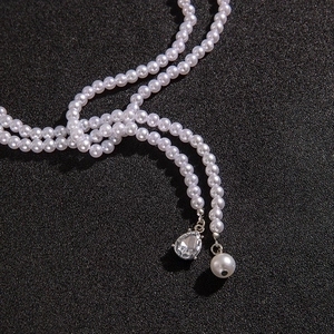 Detail of elegant pearl necklace with teardrop crystal and round pearl drop on black background