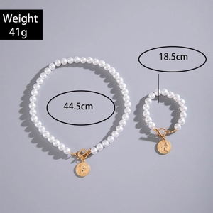 Dettaglio del set collana e bracciale di perle con chiusure a levetta dorate e ciondoli