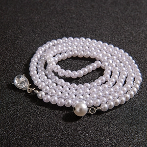 Detailed macro view of long faux pearl beaded necklace with crystal teardrop pendant