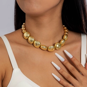 Primer plano de un collar de perlas grandes doradas con un acabado metálico brillante